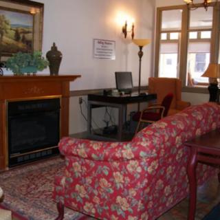 A cozy living room with a floral sofa, a fireplace, and a work desk by the window.
