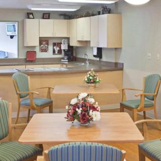 A cozy kitchen and dining area with wooden tables, cushioned chairs, and floral centerpieces.