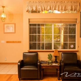 A cozy living room with two black chairs, a wooden table, and a window adorned with curtains.