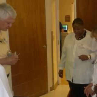 A group of people engaged in conversation indoors, possibly in a hospital setting.