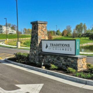 Entrance sign with a stone pillar at Traditions at Chesterfield surrounded by manicured landscaping.