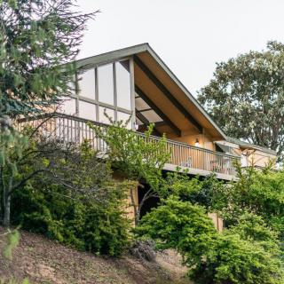 A house with a wooden balcony surrounded by lush greenery.