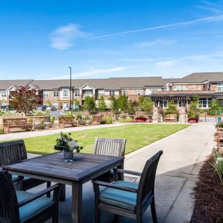 A charming residential garden with a patio set and well-maintained landscaping.