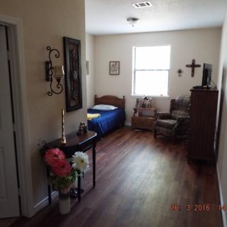 A cozy bedroom with wooden flooring, featuring a single bed, decor items, and a window letting in natural light.