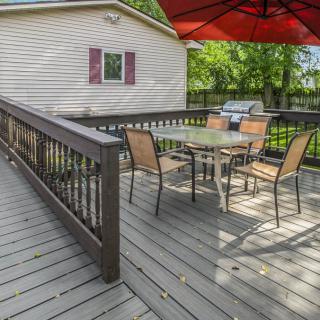 An outdoor deck with a table and chairs, shaded by a large umbrella.