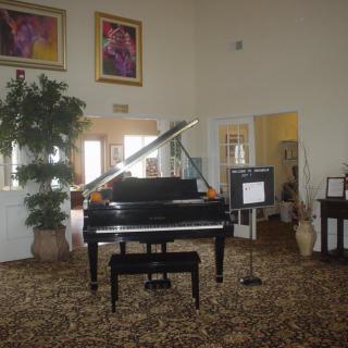 A grand piano in a well-decorated living room with artwork and plants.