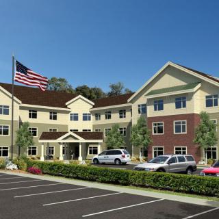 A three-story building with a parking lot and American flag in front.