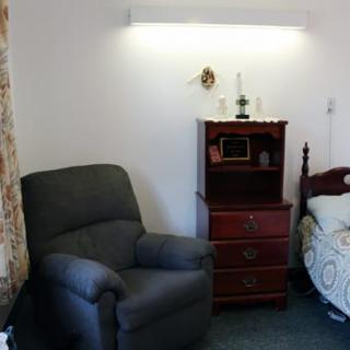 A cozy bedroom setup with an armchair and a wooden chest of drawers next to a bed.