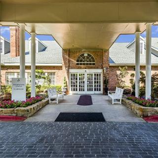 A grand entrance to a building featuring white pillars and a landscaped pathway.