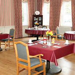 A cozy dining room with neatly arranged tables and chairs, adorned with red tablecloths.