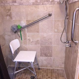 Accessible shower with a chair and grab bars for safety.