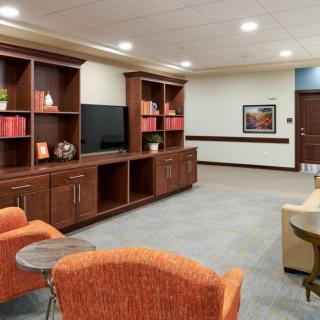 A cozy living room interior with a television, wooden shelves, and comfortable seating.