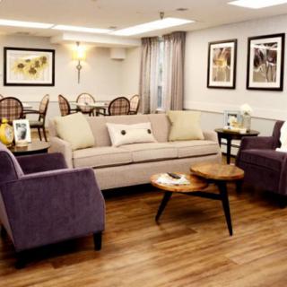 A well-decorated living room with a comfortable sofa and two chairs surrounding a wooden coffee table, featuring warm lighting and wall art.
