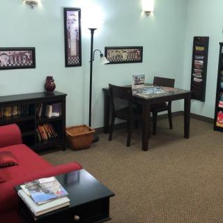 A cozy waiting room with a sofa, table, chairs, and decorative elements.