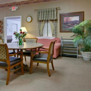 A cozy living room with a table and chairs, sofa, plants, and decorative elements.