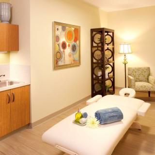 A serene and inviting massage room with a treatment table, cozy chair, and calming decor.