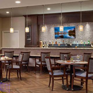 A modern restaurant interior featuring a bar and dining tables with elegant lighting and decor.