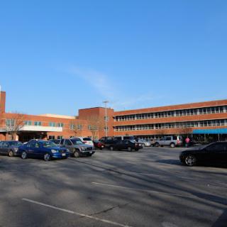 A view of a school building with a spacious parking lot under a clear blue sky.