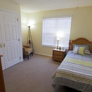A cozy bedroom with a single bed, bedside table, and floor lamp.