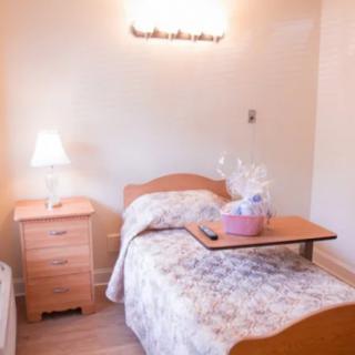 A cozy bedroom with a single bed, nightstand, and lamp.