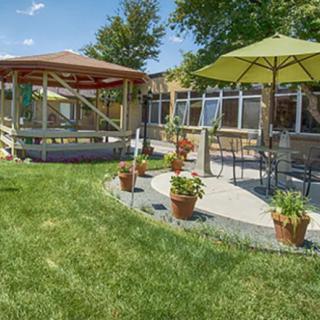 A beautiful backyard with a gazebo, patio seating, and lush green lawn.