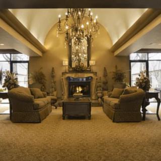 A luxurious living room featuring a grand chandelier, comfortable sofas, and an ornate fireplace.