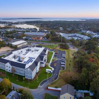 Aerial view of a coastal building surrounded by greenery at sunset.