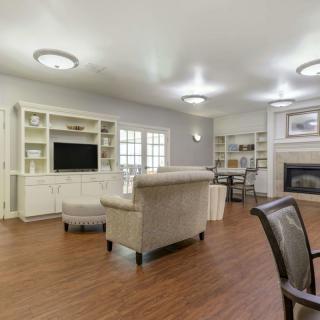 A spacious and well-lit living room featuring elegant furnishings, a television, bookshelves, and a fireplace.