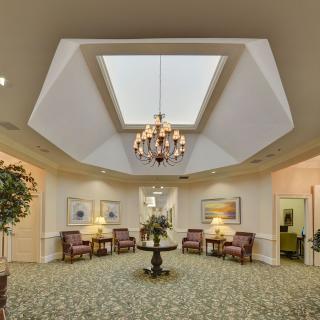 A well-lit lobby featuring a central chandelier, skylight, and comfortable seating arrangements.