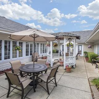 A spacious patio with outdoor furniture, including an umbrella-shaded table and chairs, set in a sunny courtyard.