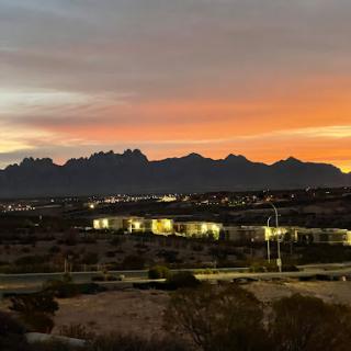 A breathtaking view of the mountains illuminated by city lights under a vibrant sunset sky.