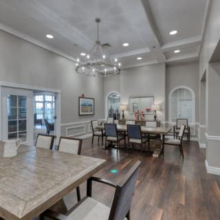 A spacious and elegantly designed dining room with a modern chandelier and hardwood flooring.
