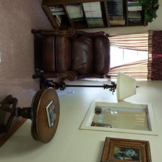 A cozy living room setup featuring a leather chair, wooden table, and a bookshelf.