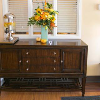 A dark wooden console table adorned with a vibrant floral arrangement in a light blue vase.