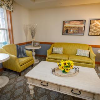 A cozy living room with yellow sofas, a white coffee table adorned with sunflowers, and tasteful wall art.