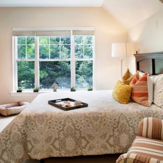 A cozy and well-lit bedroom with decorative pillows and a window view.