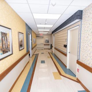A hospital hallway with patterned flooring and framed artwork on the walls.