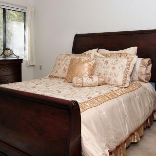 A cozy bedroom with a neatly made bed and elegant bedding.