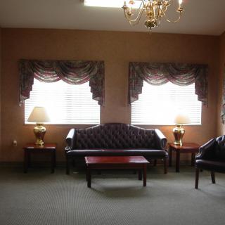 A classic living room with a sofa, tables, lamps, and draped curtains.