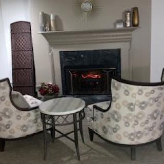 A cozy living room setup with two elegant chairs facing a lit fireplace.