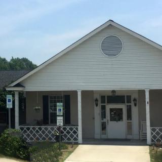 A small white building with a front porch and accessibility ramp.
