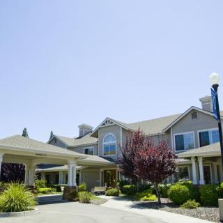 A large residential building with landscaped gardens under a clear blue sky.