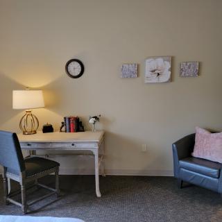 A cozy room with a desk and chair, adorned with wall art and a small sofa.