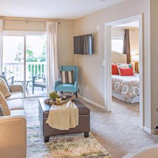 A cozy living room in an apartment featuring a couch, TV, and access to a balcony.
