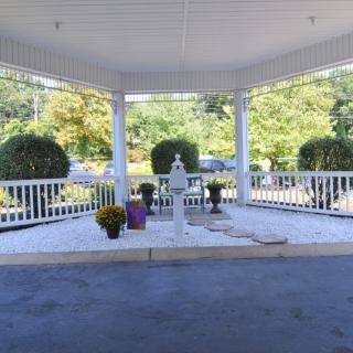 A serene outdoor gazebo with decorative flowers and a garden backdrop.