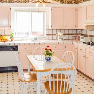 A retro kitchen with pink cabinets and a cozy dining area.