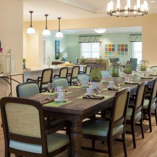 A spacious dining room with a large table set for a meal, featuring elegant lighting and comfortable seating.