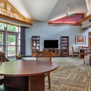 A spacious and modern lounge area featuring comfortable furniture, bookshelves, and ample natural light.