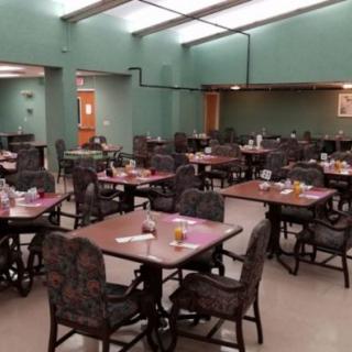 An empty dining hall with neatly arranged tables and chairs.