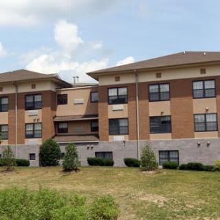 A three-story residential building with a brick facade and multiple windows.